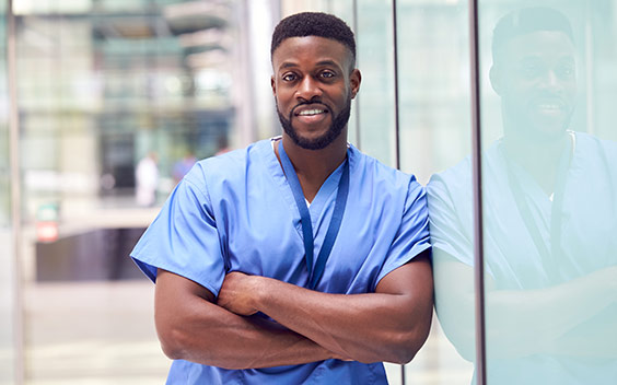 Young, Black male nurse with arms folded and smiling.